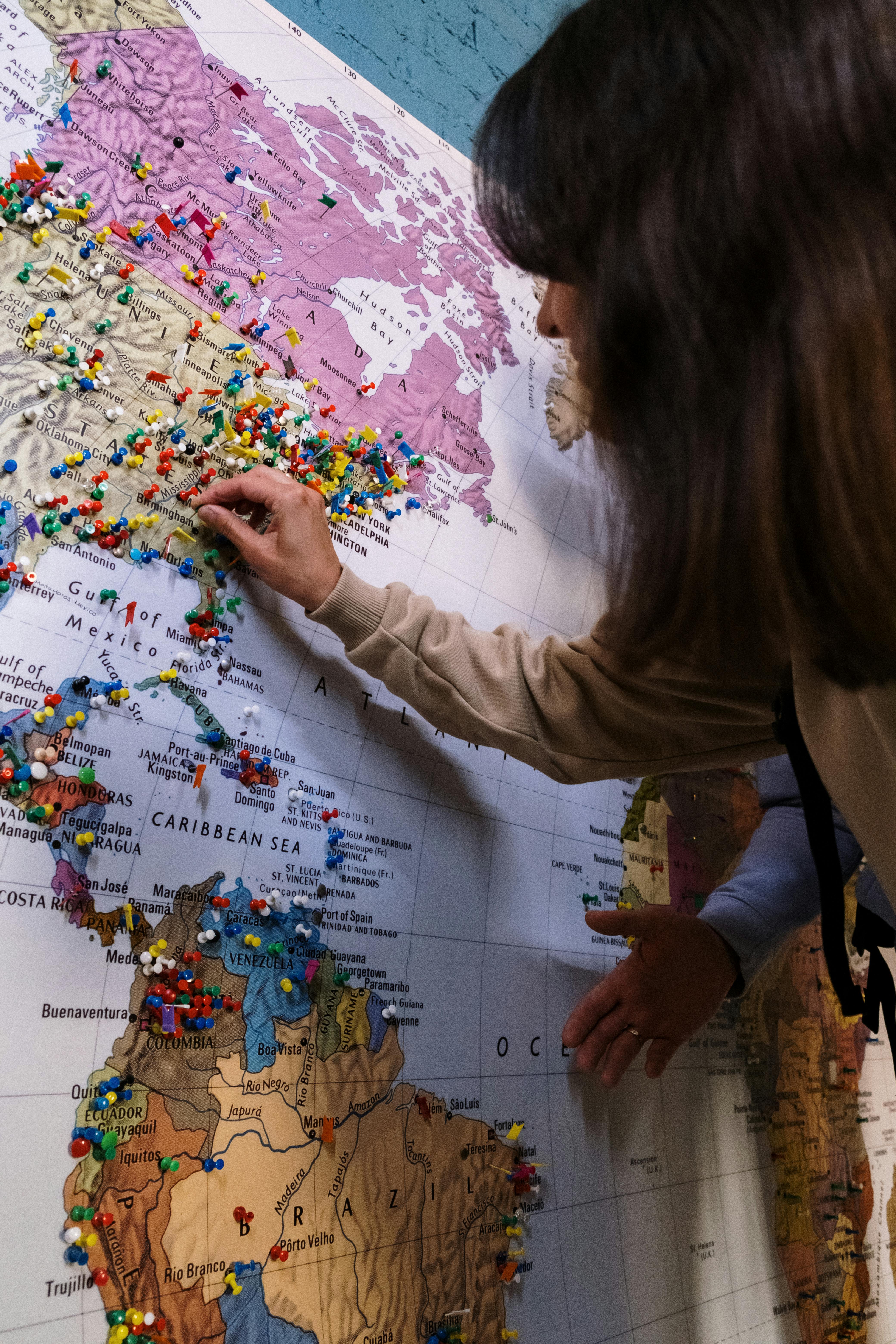 Person placing pins on world map representing Credence Global's global reach and international expansion